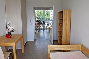 Schülerzimmer mit Bett, Nachttisch, Tisch und einem Kleiderschrank