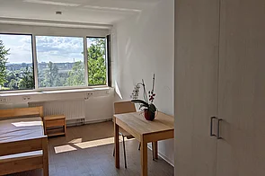 Schülerzimmer des Hufeland-Hauses mit großem Fenster, Bett, Nachttisch, einem weiteren Tisch und einem Kleiderschrank
