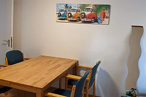 Holztisch mit 4 Stühlen an einer Wand.
